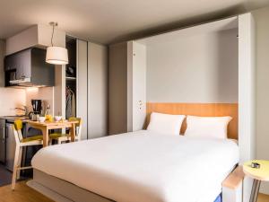 sypialnia z dużym łóżkiem i kuchnią w obiekcie Aparthotel Adagio Access Freiburg we Fryburgu Bryzgowijskim