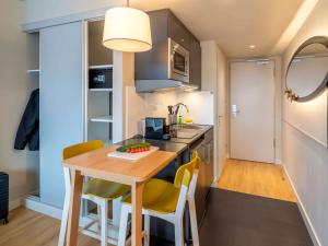 a small kitchen with a wooden table and yellow chairs at Aparthotel Adagio Access Freiburg in Freiburg im Breisgau