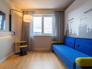 uma sala de estar com um sofá azul e uma mesa em Aparthotel Adagio Access Freiburg em Friburgo em Brisgóvia