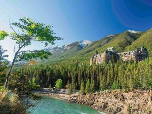 a castle on a hill next to a river at Fairmont Banff Springs in Banff