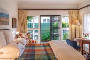 um quarto com uma cama, uma secretária e janelas em Hedge House Guest House na Cidade do Cabo