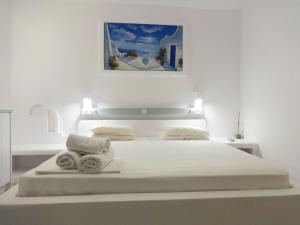 a white bedroom with a bed with towels on it at Paleochori Studios in Paliochori