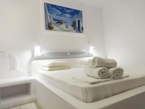 a white bedroom with a bed with towels on it at Paleochori Studios in Paliochori