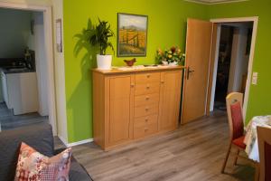 a living room with green walls and a wooden dresser at Fewo-rosenberger-sauerland in Lennestadt