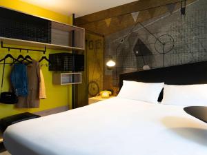ibis Styles Dreux Centre Gare في درو: غرفة نوم بسرير ابيض وجدار اصفر