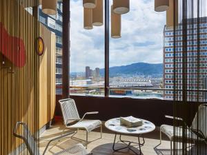 une chambre avec des chaises et une table et une vue sur la ville dans l'établissement 25hours Hotel Zürich West, à Zurich