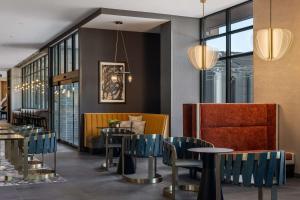 a restaurant with blue chairs and tables and windows at Tempo By Hilton Louisville Downtown Nulu in Louisville