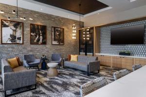 a lobby with chairs and a tv on a brick wall at Tempo By Hilton Louisville Downtown Nulu in Louisville