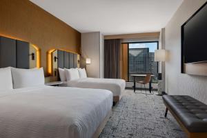 a hotel room with two beds and a flat screen tv at Tempo By Hilton Louisville Downtown Nulu in Louisville