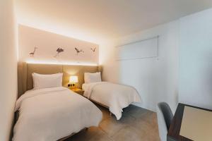 Radisson Blu Aruba في شاطئ بالم إيغل: غرفة نوم بسريرين مع ملاءات بيضاء وطيور على الحائط