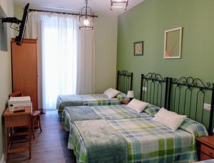 2 camas en una habitación con paredes verdes en Hospedaje Don Pelayo, en Gijón