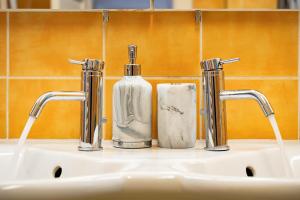 un lavandino in bagno con due rubinetti e una bottiglia di sapone di Kingdom of Skylight a Praga Altre 40 foto