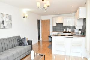 a living room with a couch and a kitchen at Sleeps 4 - Private Balcony - Wheelchair Accessible in London