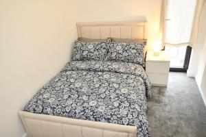 a bedroom with a bed with a blue and white comforter at Sleeps 4 - Private Balcony - Wheelchair Accessible in London