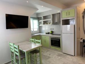 Aphrodite Hotel & Apartments في إيوس خورا: مطبخ مع طاولة وثلاجة بيضاء