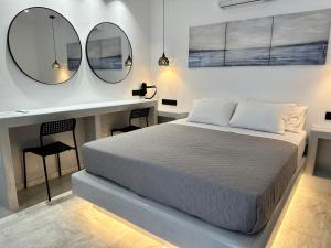 Aphrodite Hotel & Apartments في إيوس خورا: غرفة نوم بسرير ومرآتين على الحائط