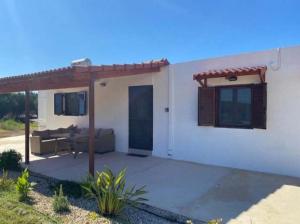 une maison blanche avec une pergola et une terrasse dans l'établissement Haroupia, à Elafonisi