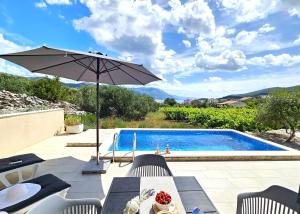 a patio with an umbrella and a swimming pool at Stone house in vineyard in Račišće
