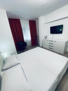 a hotel room with a white bed and a television at La Burini in Vaslui