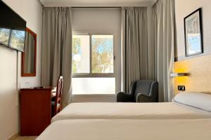 a hotel room with two beds and a chair and a window at Hotel Don Ignacio in San José