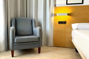 a blue chair in a room next to a bed at Hotel Don Ignacio in San José