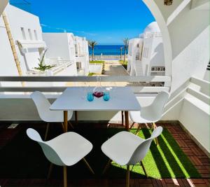 a table and chairs on a balcony with the ocean at La Baie in Harqalah
