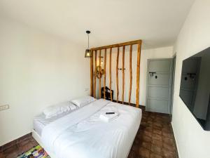 a bedroom with a white bed and a television at Taouarguit Guest House in Imsouane