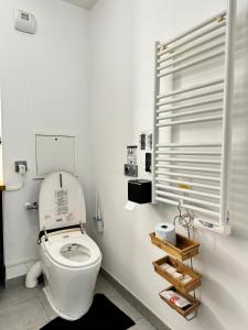 une salle de bains blanche avec des toilettes et une étagère. dans l'établissement The Green Terrace Disneyland, à Chessy