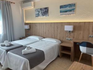 a hotel room with two beds and a chair at Hostal Santa Clara in L'Estartit
