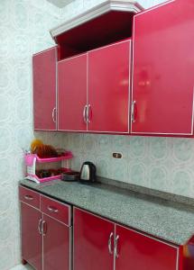 uma cozinha com armários vermelhos e uma bancada em شقة الولاء Loyalty apartment em Dumyat al Jadidah