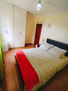 a bedroom with a bed with a red and yellow blanket at Mara Haven - Thika Greens Estate in Thika