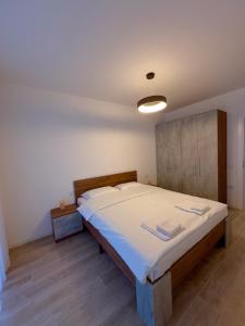 a bedroom with a large bed with white sheets at Holiday Apartments Gjakova in Gjakove