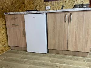 a white refrigerator in a kitchen with wooden cabinets at Mountain peaceful cottages in Žabljak +53 photos