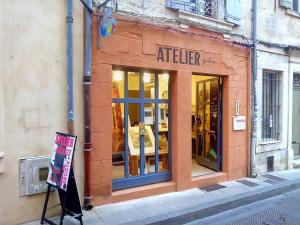 un frente de tienda con un cartel delante en Le nid des Arènes, en Arles