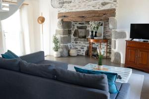 ein Wohnzimmer mit einem blauen Sofa und einem Steinkamin in der Unterkunft Jolie maison de vacances à 5 mn à pied des plages in Landéda