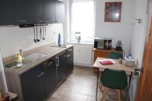 uma cozinha com armários pretos, uma mesa e um lavatório em Ferienwohnung am Windberg em Freital
