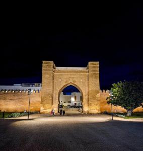 a large building with an arch at night at Dar ZENATI in Rabat