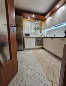 a large kitchen with white cabinets and a door at Cozy Place - в центъра, само на 5 минути пеша от плажа in Burgas +18 photos