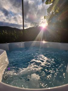 una bañera llena de agua con el sol en el fondo en Cabana Hostel nas Árvores EcoPark en São Pedro
