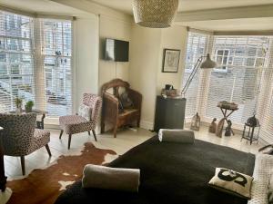 a living room with a couch and chairs and windows at Seaforth St Ives in St Ives