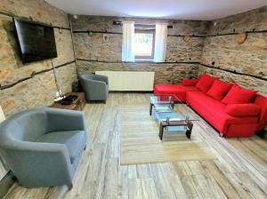 a living room with a red couch and two chairs at Traditional Stone Villa "To Petrino" in Florina