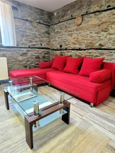 Sofá rojo en una habitación con pared de piedra en Traditional Stone Villa "To Petrino", en Florina