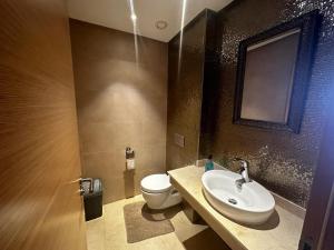a bathroom with a white toilet and a sink at Luxueux Appartement Plage des Nations in Sidi Bouqnadel +12 photos