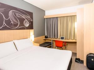 um quarto de hotel com uma cama e uma secretária e uma cama e um quarto em ibis Bacabal em Bacabal