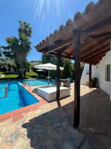 a pool with a wooden pergola next to a house at Country House with Pool and Big Garden in Oropós