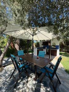 einen Holztisch mit zwei Stühlen und einem Sonnenschirm in der Unterkunft Country House with Pool and Big Garden in Oropos