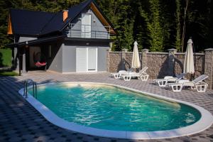 a swimming pool with chairs and a house at Villa Akish in Bijeljina
