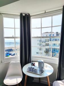 een woonkamer met een tafel en 2 ramen bij Horizon in Brighton & Hove