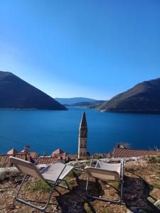 a couple of chairs and a clock tower next to a lake at Apartman Dado in Perast