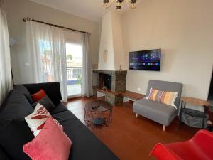 a living room with a black couch and a fireplace at Gaia Apartments in Hanioti